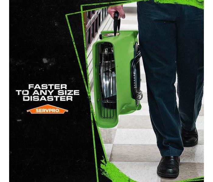 SERVPRO tech carrying drying equipment with the caption: FASTER TO ANY SIZE DISASTER.